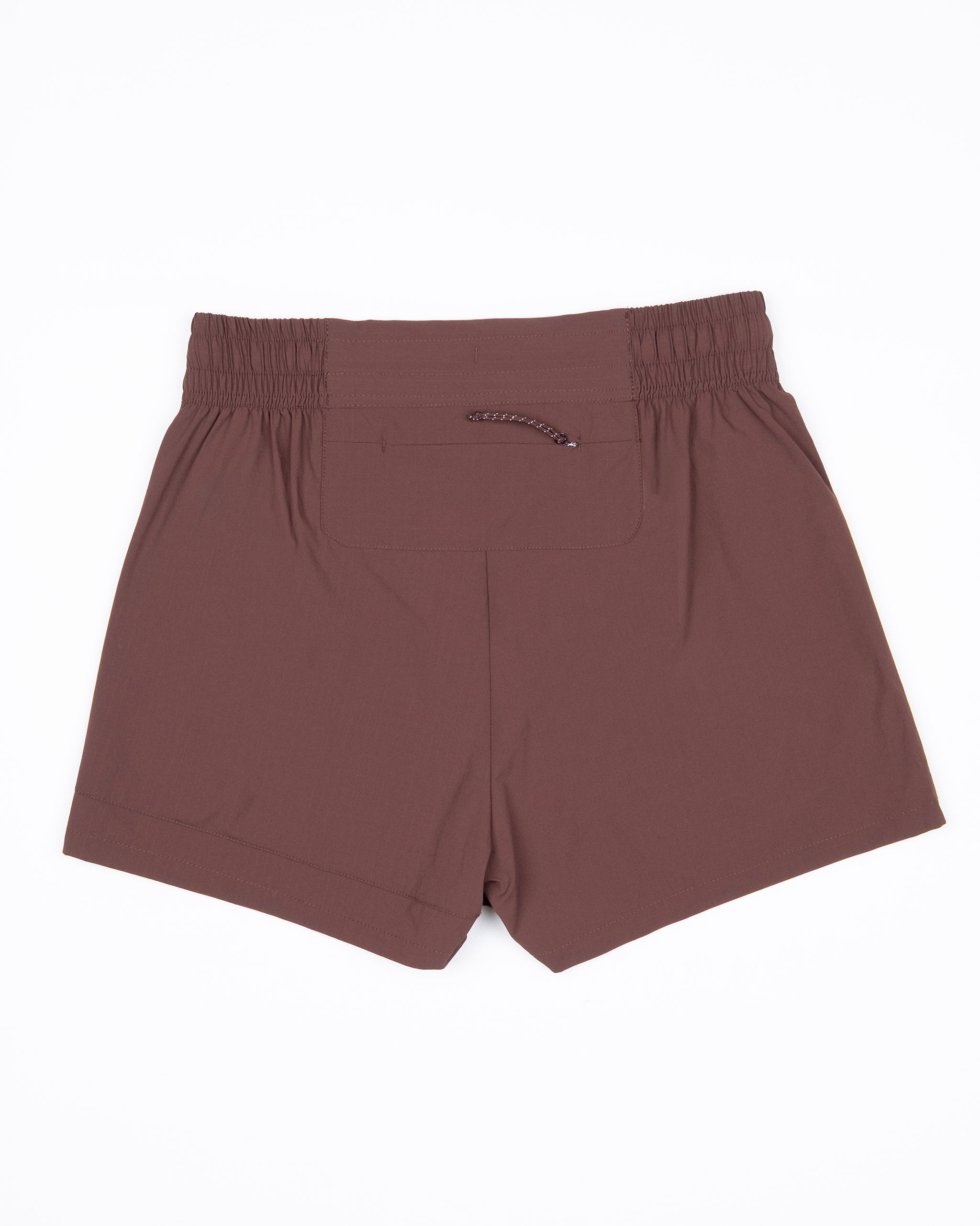 The BEARDEDGOAT Women's Alpina Short is a brown, high-waisted adventure short with an elastic waistband, single back pocket, and durable ripstop fabric. Shown flat on white, it offers a relaxed fit and minimalist design.