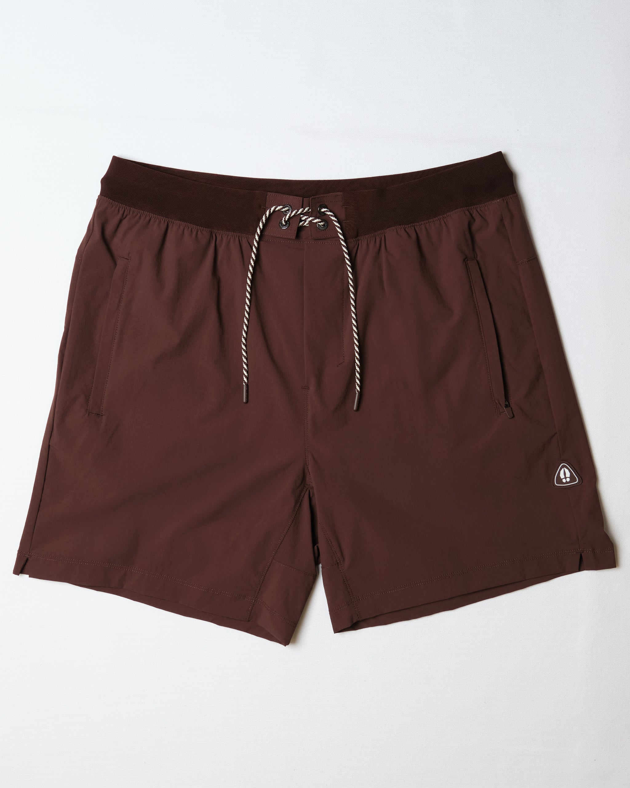 The BEARDEDGOAT Men's Rambler Short in dark brown features 4-way stretch fabric, an elastic waistband, white and brown drawstring, side pockets, and a small logo—perfect for trail running.