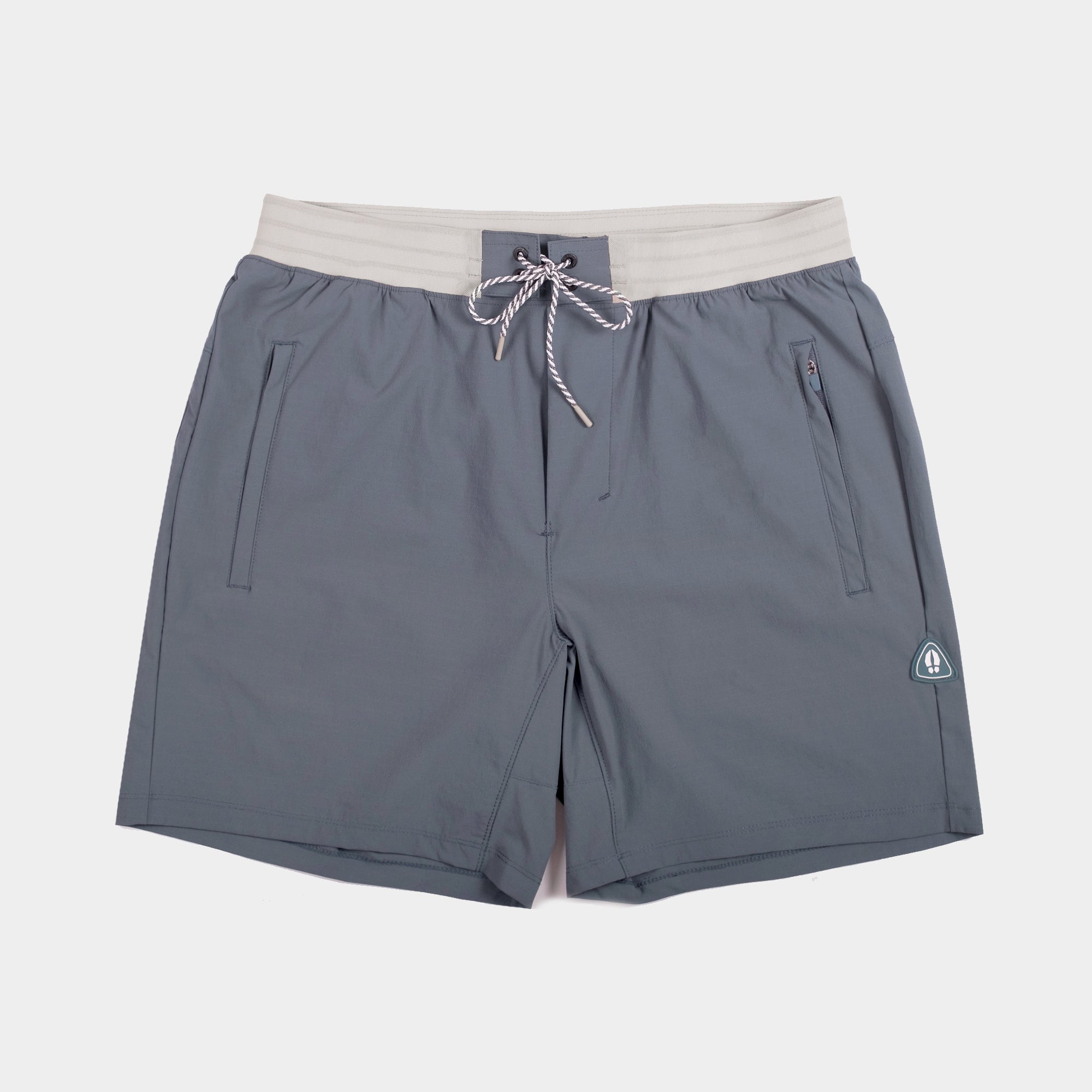 The beardedgoat Mens Rambler Short features a light gray waistband, drawstring closure, two front pockets, a zip pocket for essentials, and a small logo patch on the left leg. Designed for extreme movement and shown laid flat on a white background.