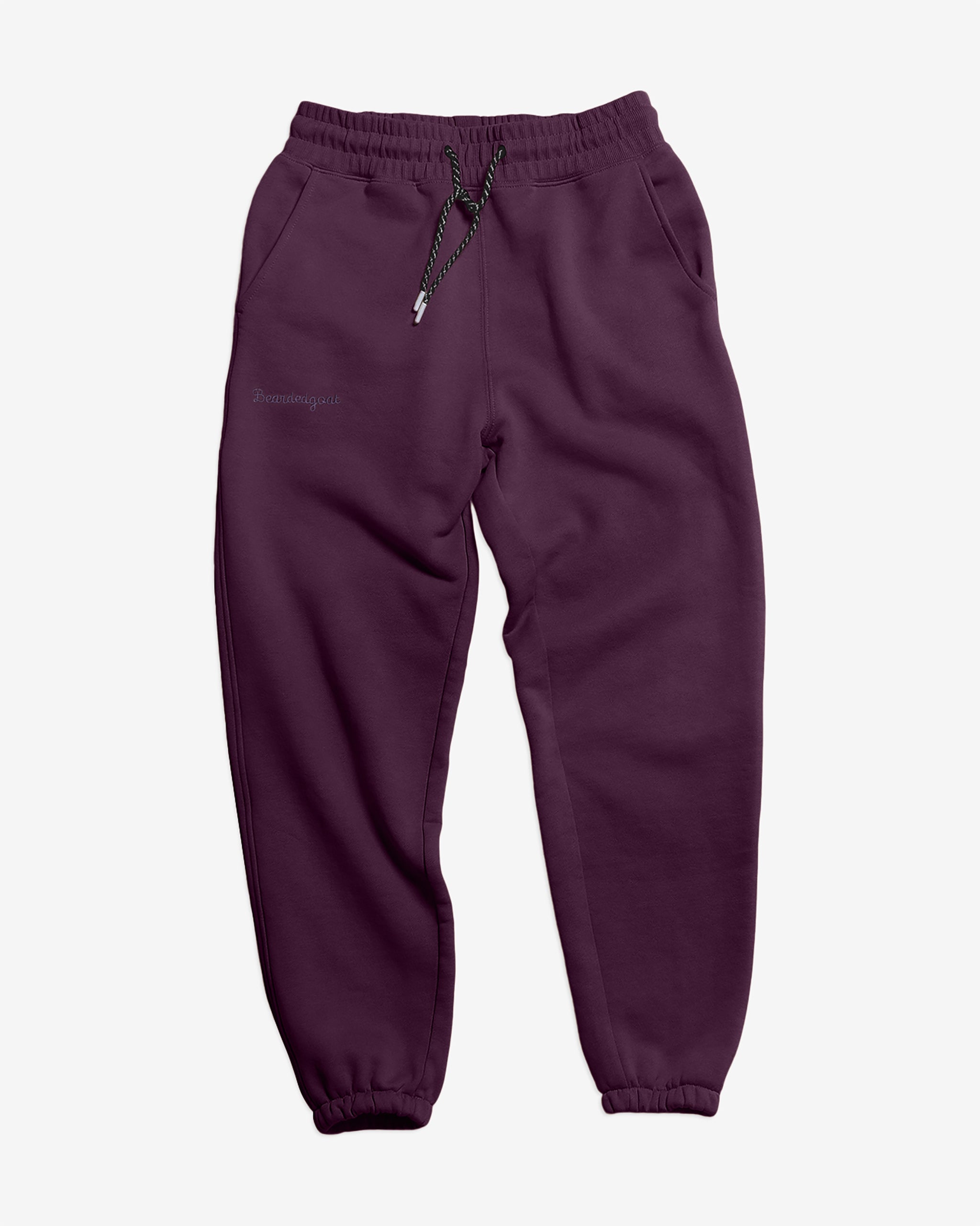 The BEARDEDGOAT NEW — Overnight™ Classic Jogger in deep purple is made from heavyweight cotton fleece, with a high-rise waistband, black and white drawstring, side pockets, and elastic ankle cuffs, shown on a white background.